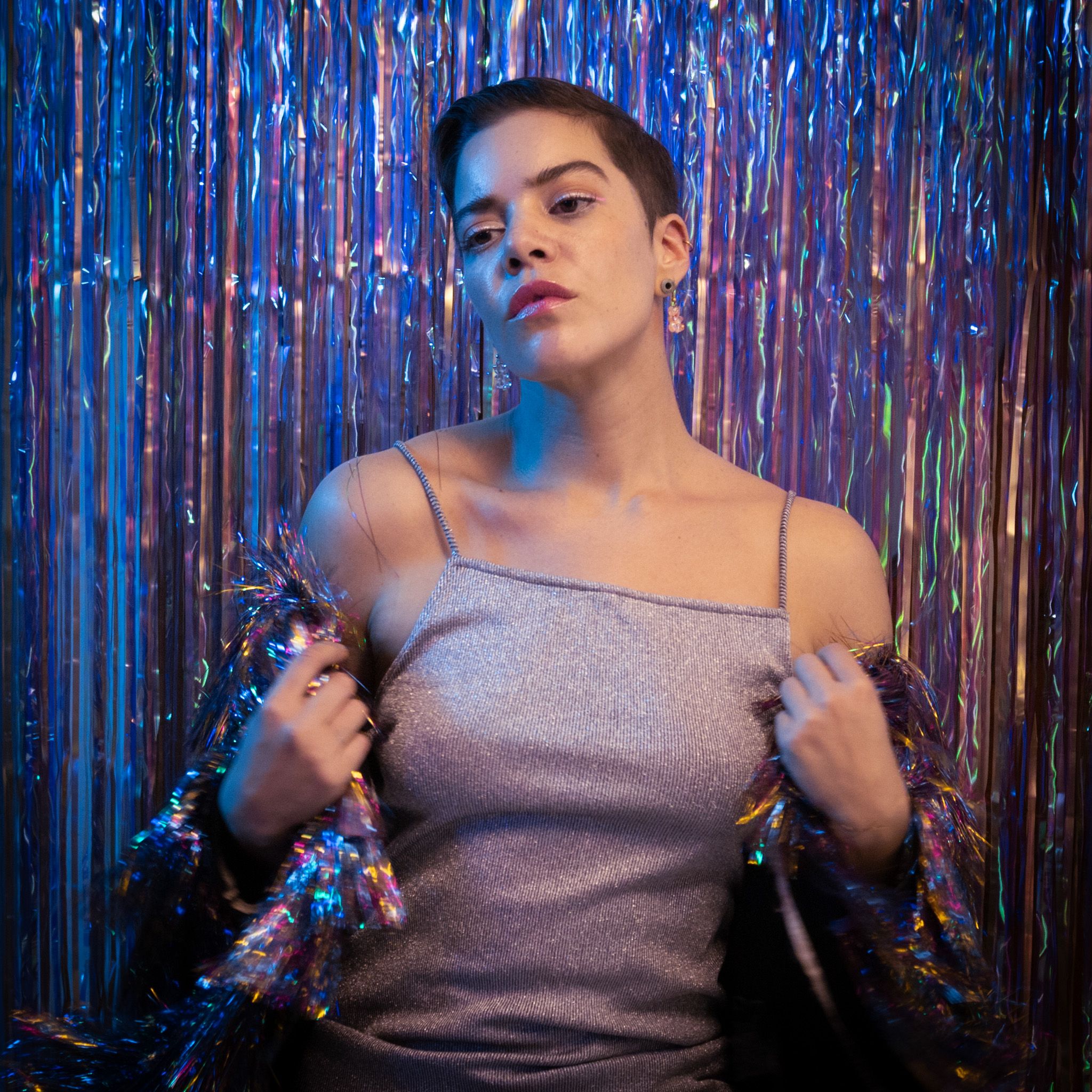Elegant portrait of a stylish woman in a shimmering dress with a reflective backdrop, creating a glamorous look.