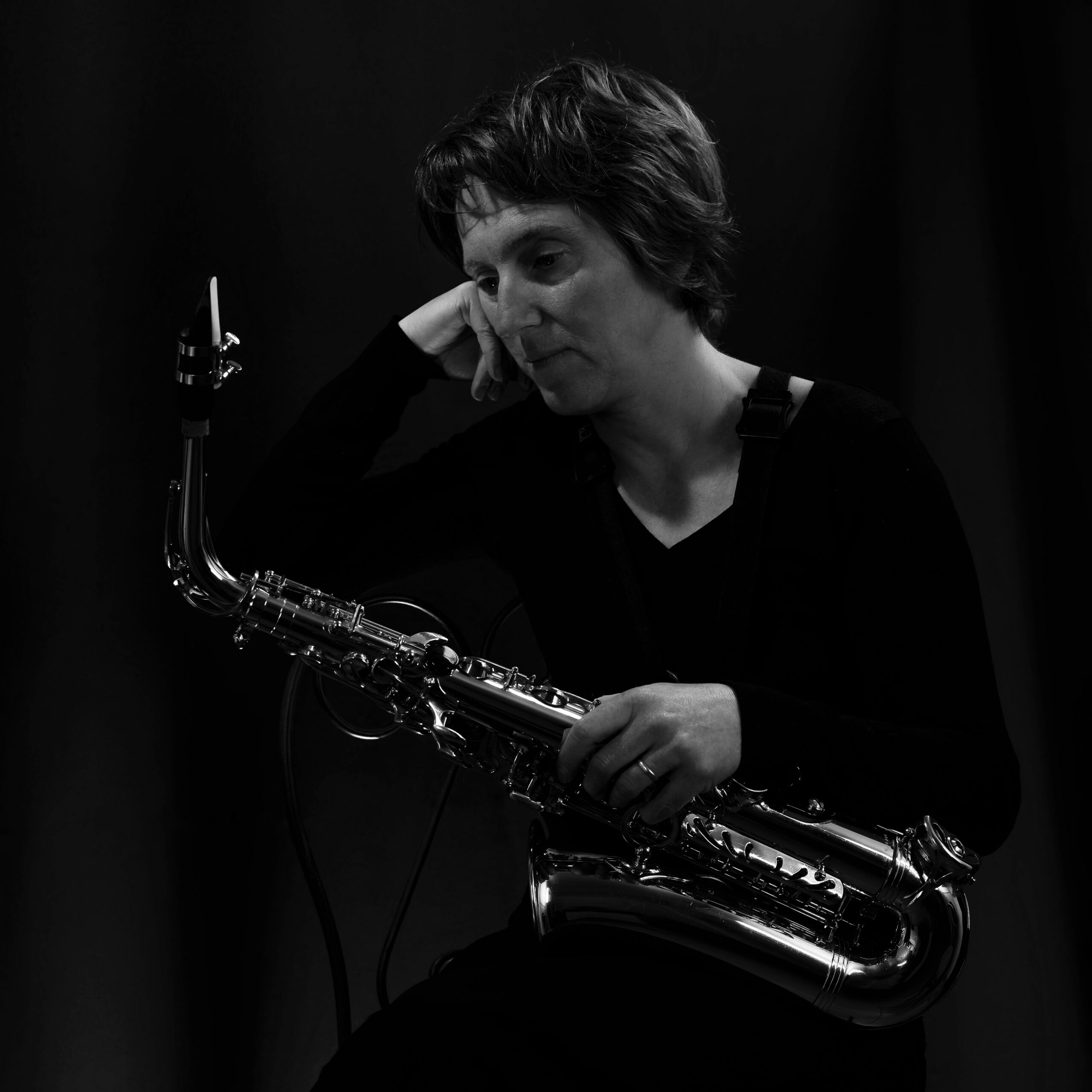 Moody black and white portrait of a female saxophonist lost in thought.